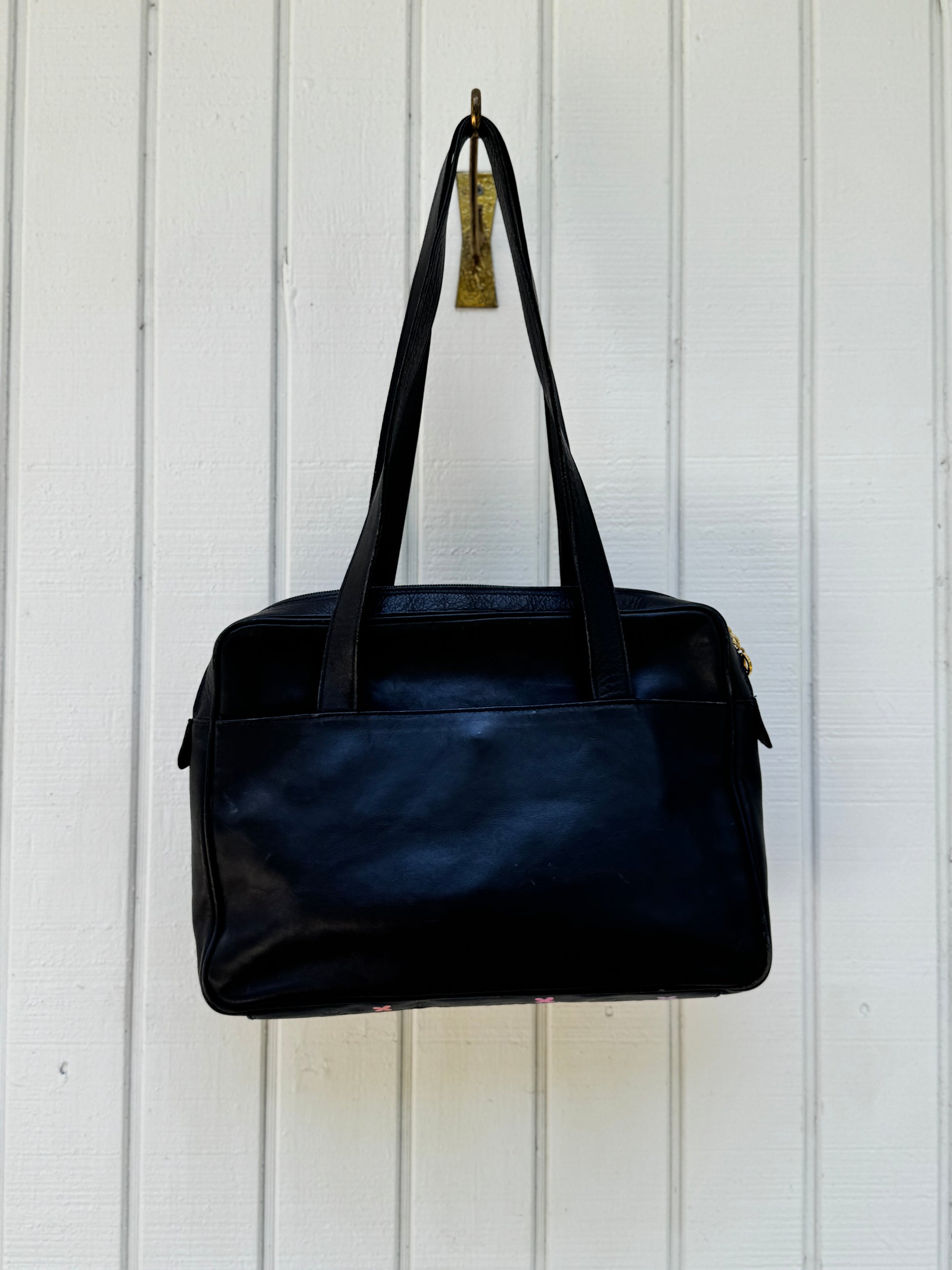 Navy leather bag by Paloma Picasso. This bag is from the 1990s. I painted multicolored flowers on it using Posca paint pens. The purse has shoulder straps with the iconic ‘X’ gold tone metal hardware linking them to the purse.

This is a photo of the back where I left it blank.