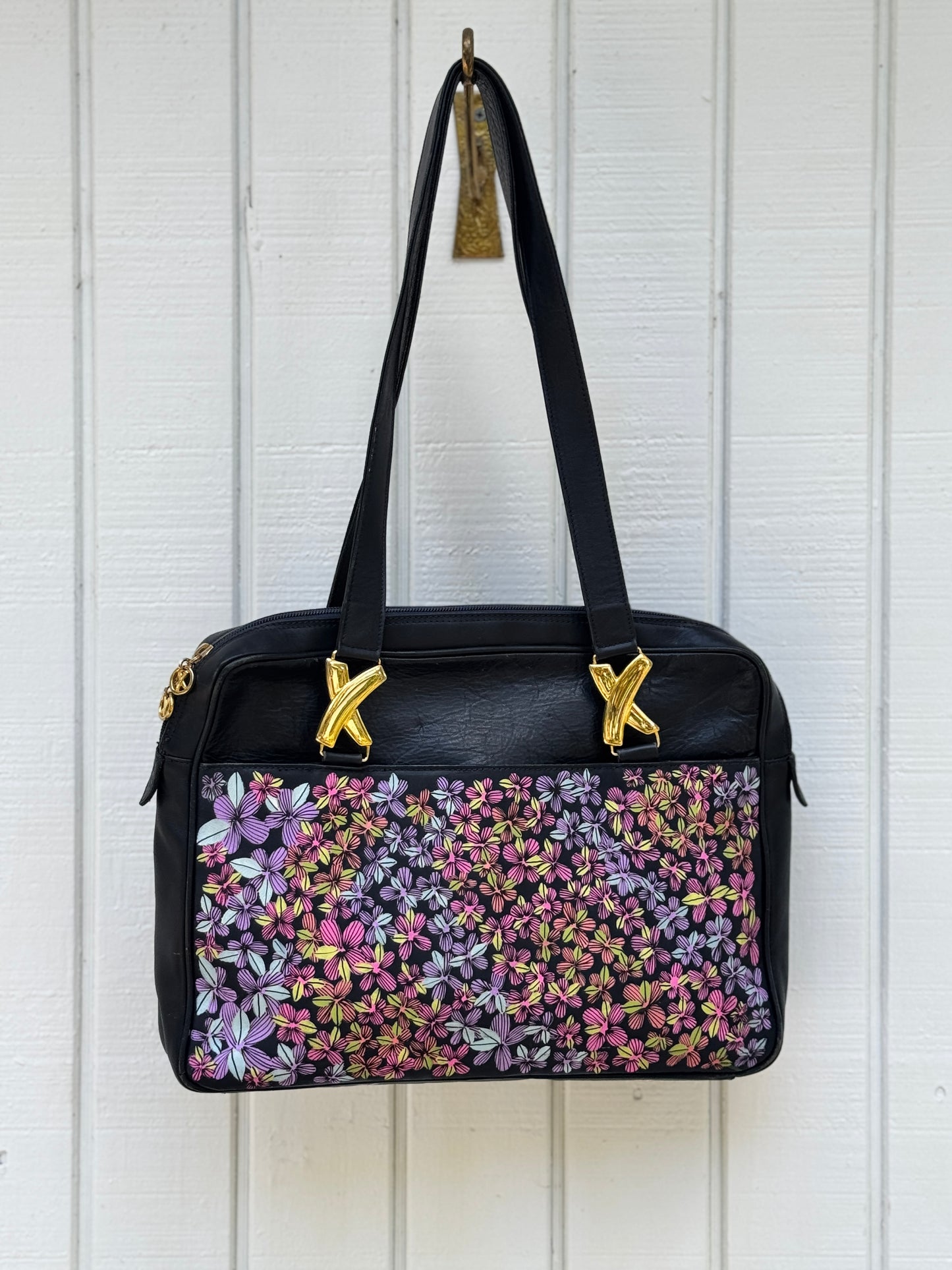 Navy leather bag by Paloma Picasso. This bag is from the 1990s. I painted multicolored flowers on it using Posca paint pens. The purse has shoulder straps with the iconic ‘X’ gold tone metal hardware linking them to the purse.