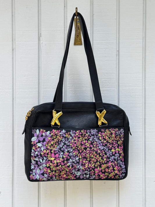 Navy leather bag by Paloma Picasso. This bag is from the 1990s. I painted multicolored flowers on it using Posca paint pens. The purse has shoulder straps with the iconic ‘X’ gold tone metal hardware linking them to the purse.